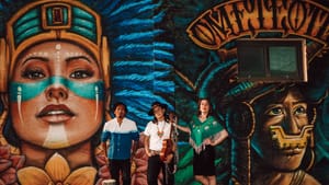 The three pose in front of Aztec mural