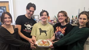 A group of teens in a classroom setting standing together, posing for a group photo