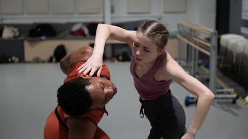 Jackson intently but gently uses her angled arm to bend Kelly, a Black male dancer, gracefully to the side by his neck.