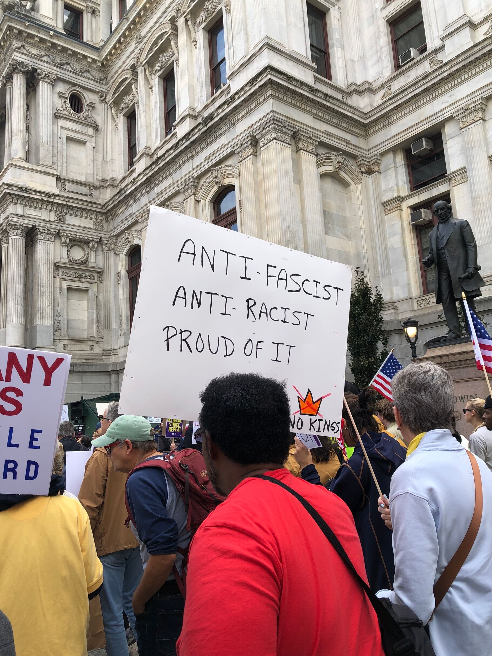 View of an October NO KINGS protest at City Hall shows a man with a handwritten sign: Anti-fascist, anti-racist, proud of it