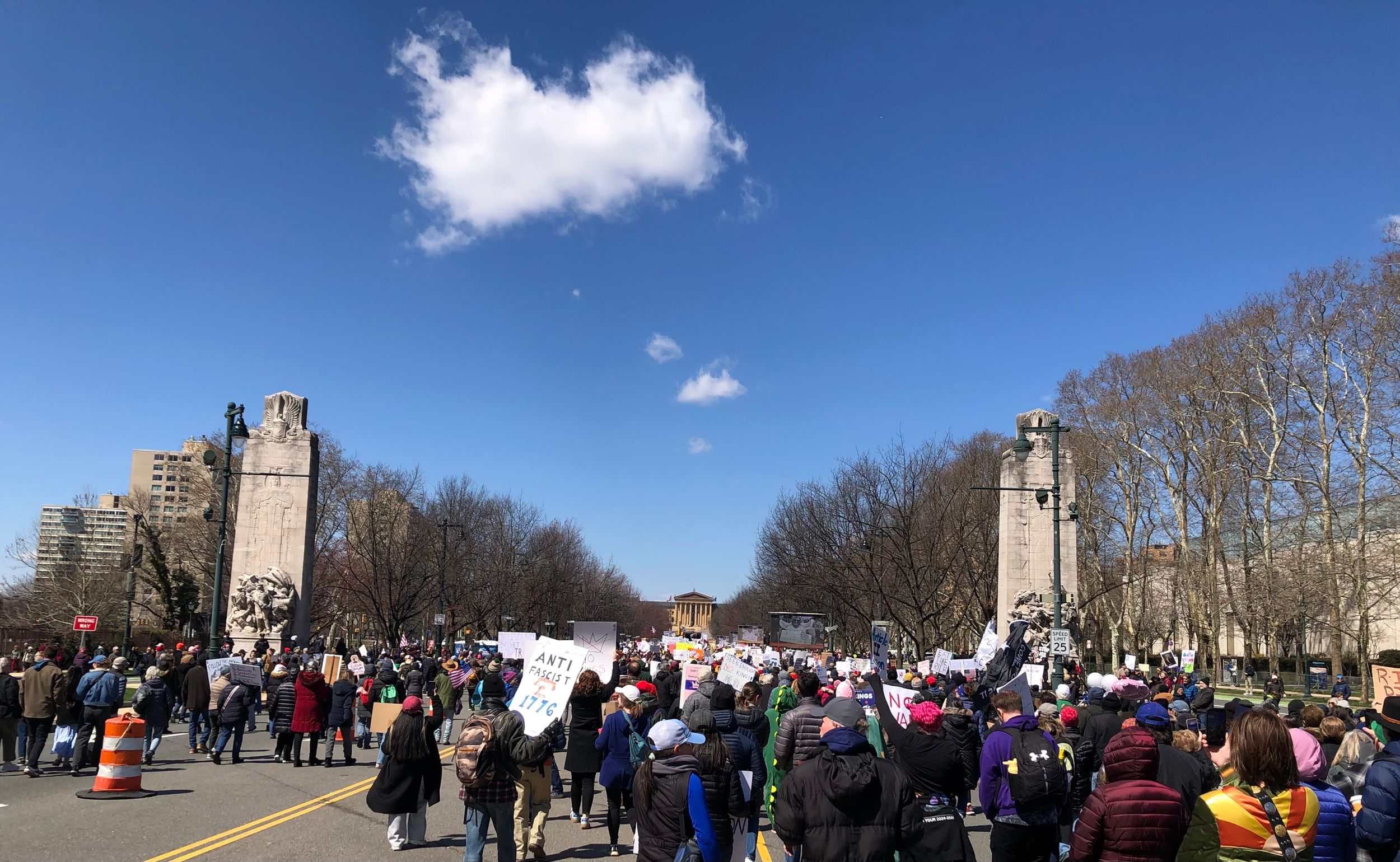 View looking north on the Parkway as thousands of people walk between tall obelisks toward the distant Art Museum steps.