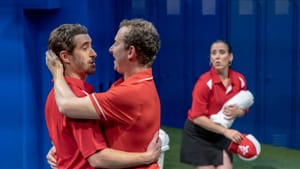 Scammell and Sheppard, in red athletic polos, embrace romantically while Minora looks on worriedly in the background.