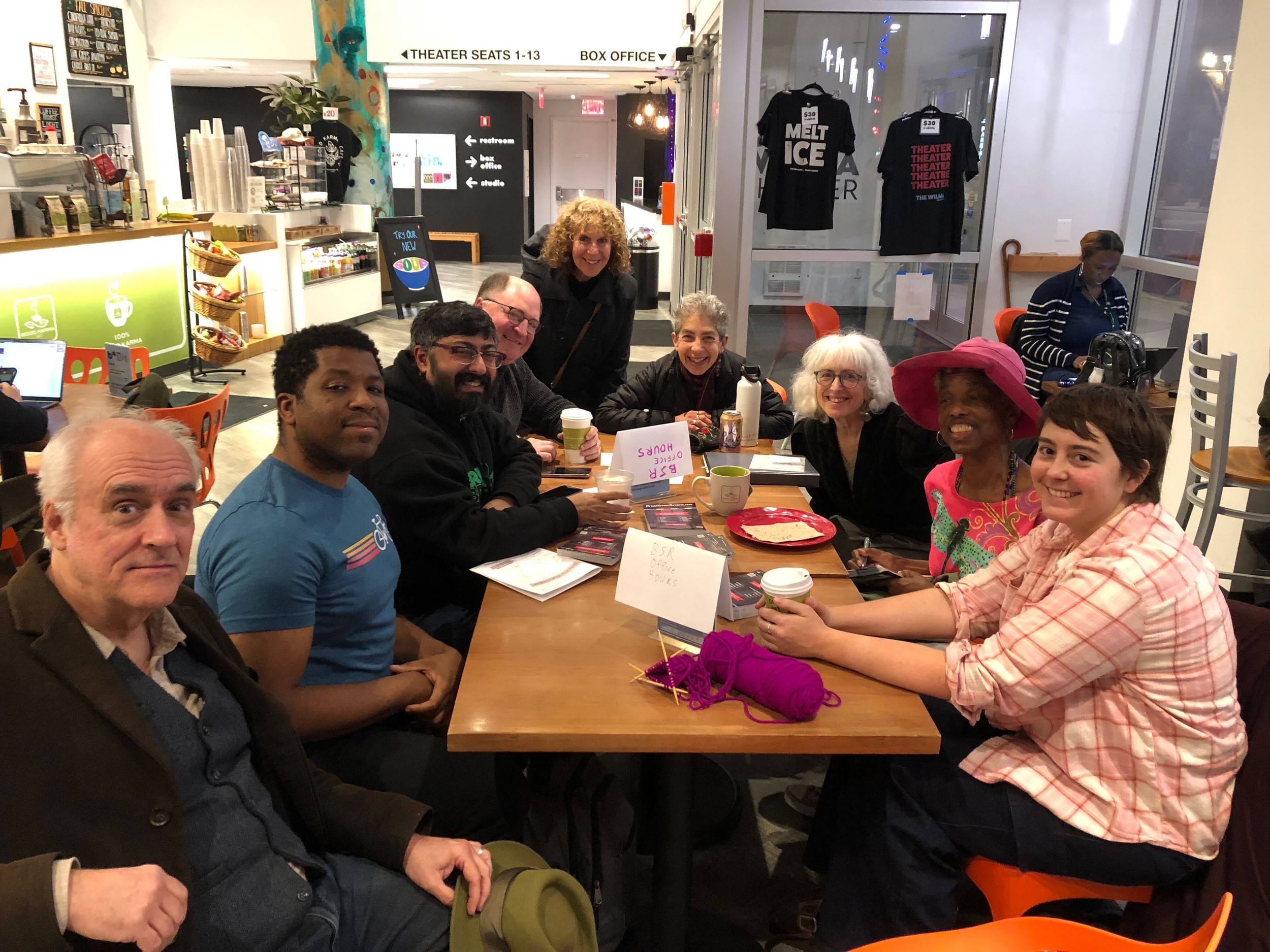 A group of people sit around a table and look at the camera