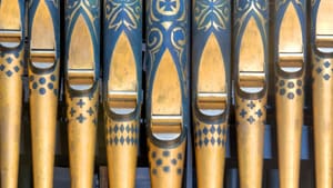 Close up details of organ pipes, rustic and with blue and gold, patterns painted on them