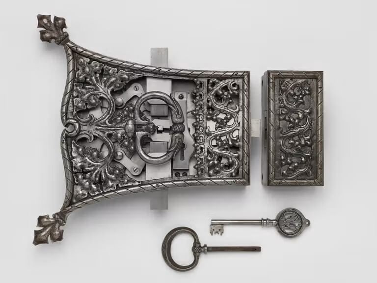 Closeup of Yellin’s bright pewter-like lock, key, and handle set, with ornate Medieval-style design details.