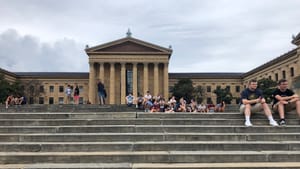 The Art Museum, with its giant east stairway large in the foreground. Higher up, people sit in groups on the steps.