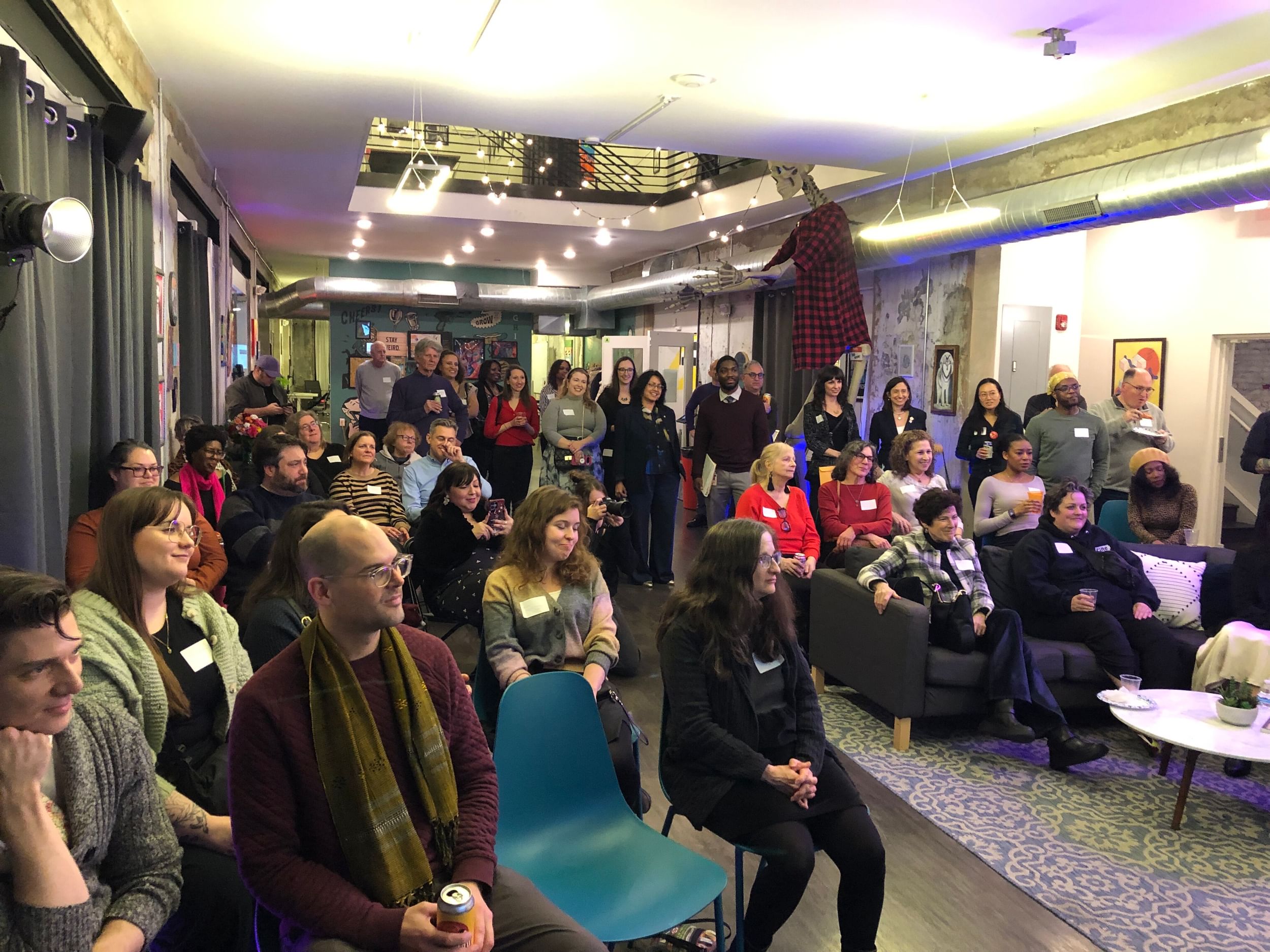 View from the podium of a diverse crowd of about 60 people in an artful venue.