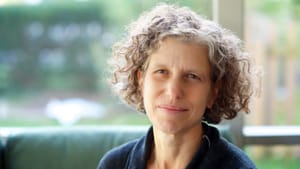 Pastan poses for an author photo, a window behind her casting light with an out-of-focus outdoor backdrop behind her