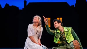 O’Hare and Ramirez sit on the stage in simple but fanciful costumes, looking joyfully upward as Ramirez points to the sky.