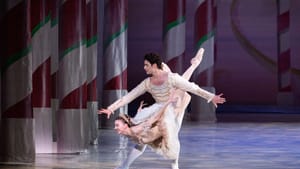 Baca, with arms spread, supports Dolan’s body as she swoops in a downward curve, a knee around his waist. They wear white.