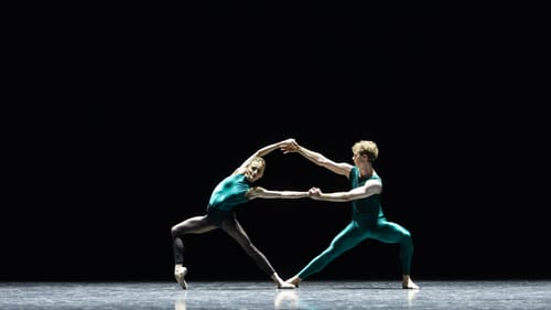 Maslova & Thomas, in shiny green leotards, lean tensely apart despite their joined arms & one foot each joined on the ground