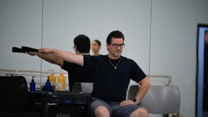 Sitting on a chair in the studio with a mirror behind him, Corella gestures to one side with a severe, focused expression.