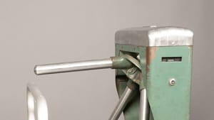 A single vintage turnstile with an olive green body and bright metal arms.