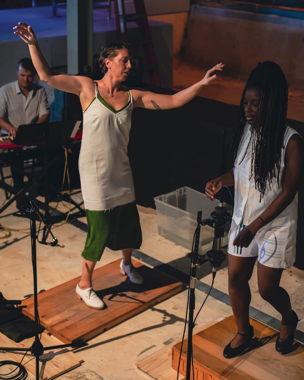 Hetherington, a white woman, and Roberson, a Black woman, perform together, each dancing on their own low wooden platform.