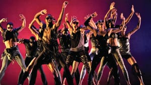 About a dozen dancers in fishnets, prints, fringe, fur, leather & sunglasses strike the same pose with arms joyfully aloft