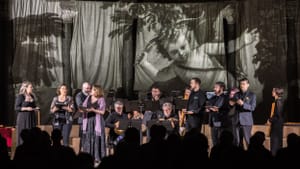 14 period musicians & vocalists perform on a chancel with a flying Renaissance Cupid projected large on a curtain behind them