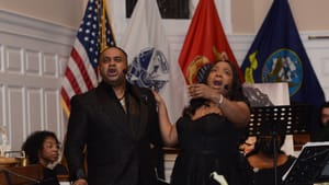 Two singers. Dressed in all black, singing on stage towards the audience.