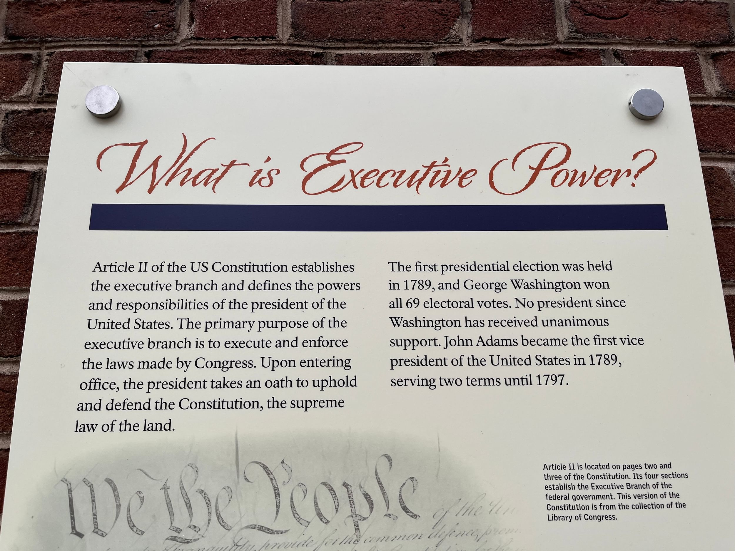Large beige informational panel with small text and red title script that says “What is executive power?”