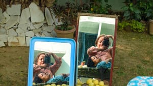 Outside, in front of a pile of lemons, two mirrors capture Mukherji and her mother making a dual portrait.