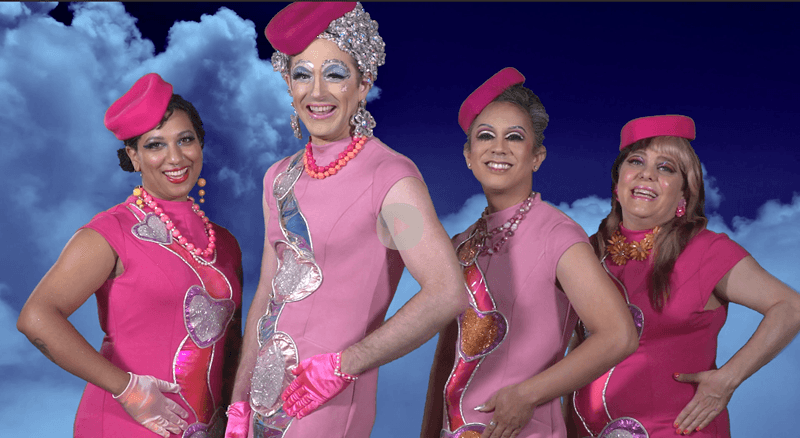 Four people in glam, appliqued, pink cap-sleeve flight attendant dresses, posing smiling together with one hand on hip.