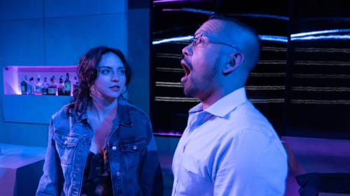 In a wash of blue light, Garcia looks angrily at Jain, who opens his mouth as if yelling in dismay.