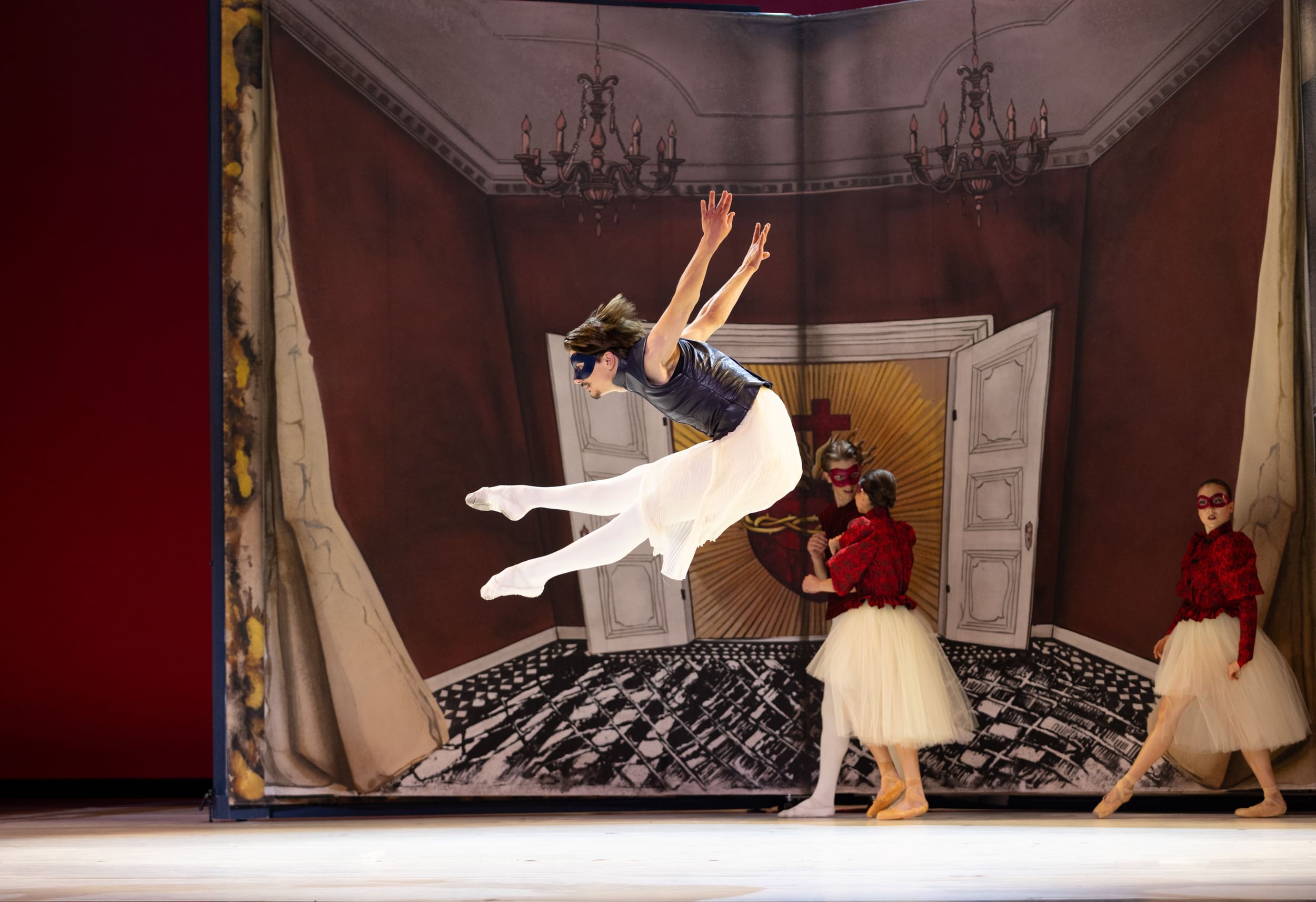 Against a backdrop like a giant storybook ballroom, Hollis leaps in profile, legs straight in front and arms flung behind.