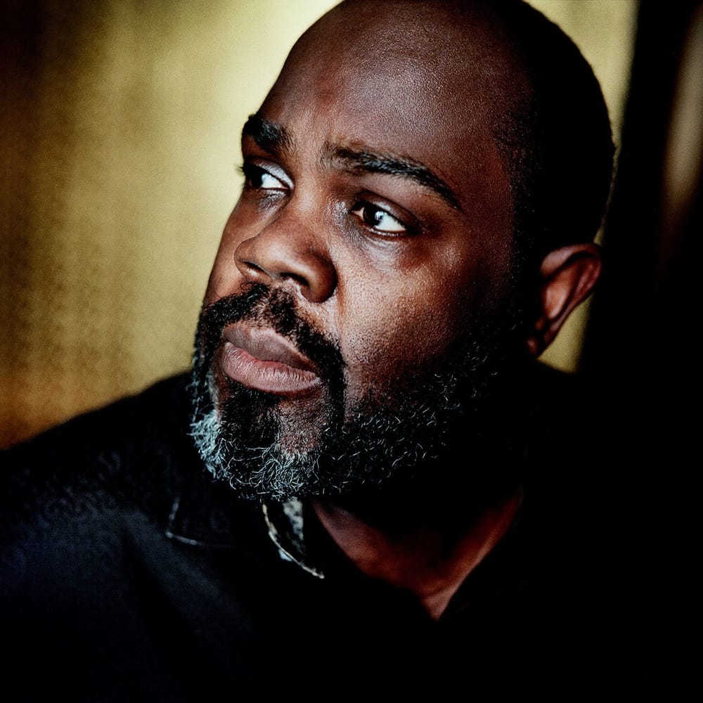 Close-up portrait shot of Mobley, a Black man with a full beard, dark with some light gray, looks on towards left of frame