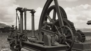 A black-and-white print of a giant metal machine with arms, pillars, and wheels. It’s outdoors under a partly clouded sky