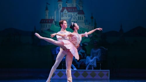Two teen dancers, the girl posing on pointe with arms & leg extended, the boy with hands at her waist.