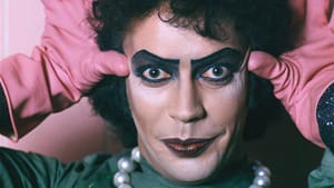 Dr. Frank-N-Furter, as played by Tim Curry, in make up and wearing pearls and gloves, eyes straight at the camera