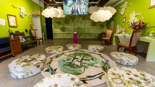 Comfy green-painted room with various antique furniture around a circular green & white rug showing entwined human fetuses.