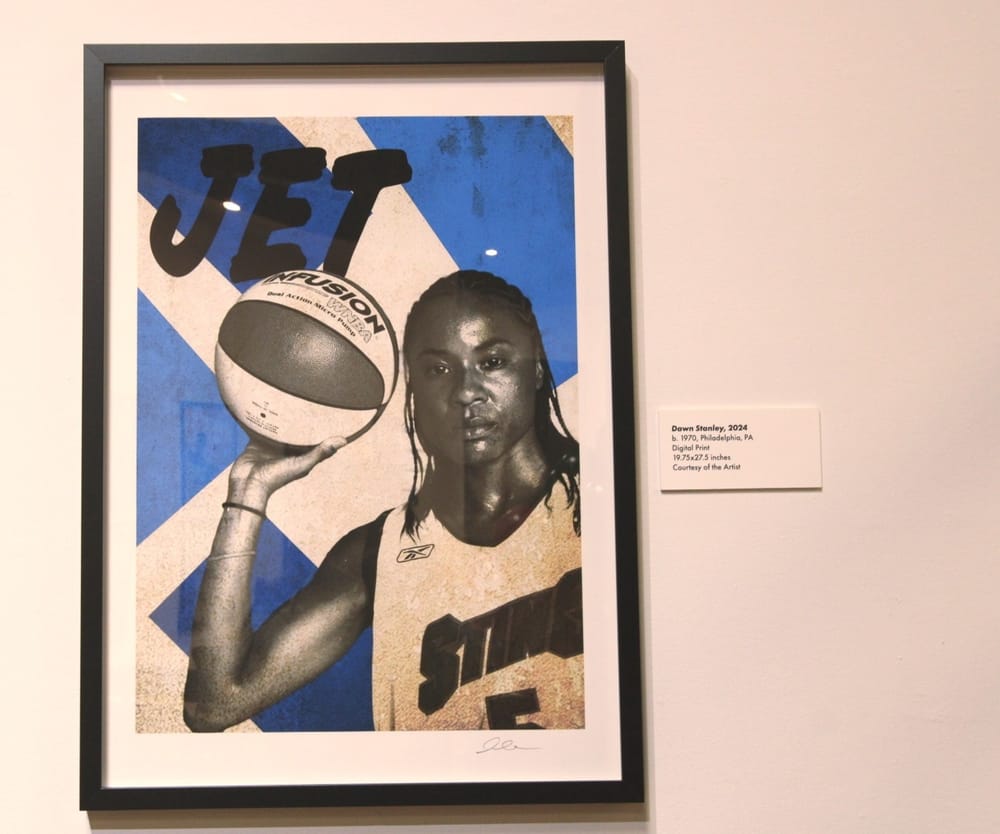 Black & white image of Dawn Stanley holding up a basketball, with a serious expression, on geometric blue & white background