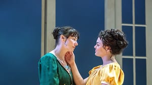 Elinor in green and Marianne in yellow, in empire-waisted dresses, look tenderly at each other, sharing a caress.