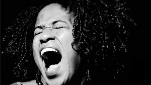 A portrait of Norris. She's singing, her mouth agape and hands open, her eyes closed. The photo is in black and white