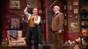 A scene from the play. The ornate set is crammed with Victorian details. Peakes talks and gestures to Van Horn.
