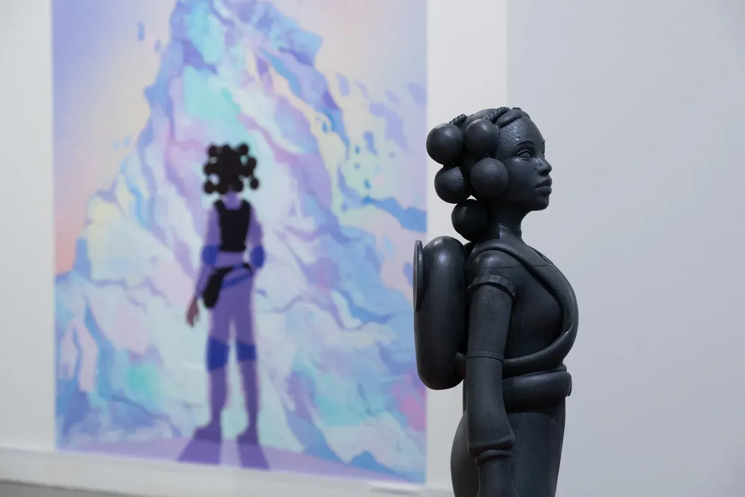 A gray sculpture of a Black woman with a backpack stands in front of an illustration with light blues and purples.