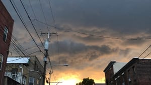 Sunset facing west on a South Philly street: pearly gray clouds give way to a golden sun where all the horizon lines converge