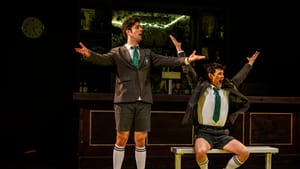 In prep school uniforms, the actors pose with arms outspread as if screaming at a sports game.