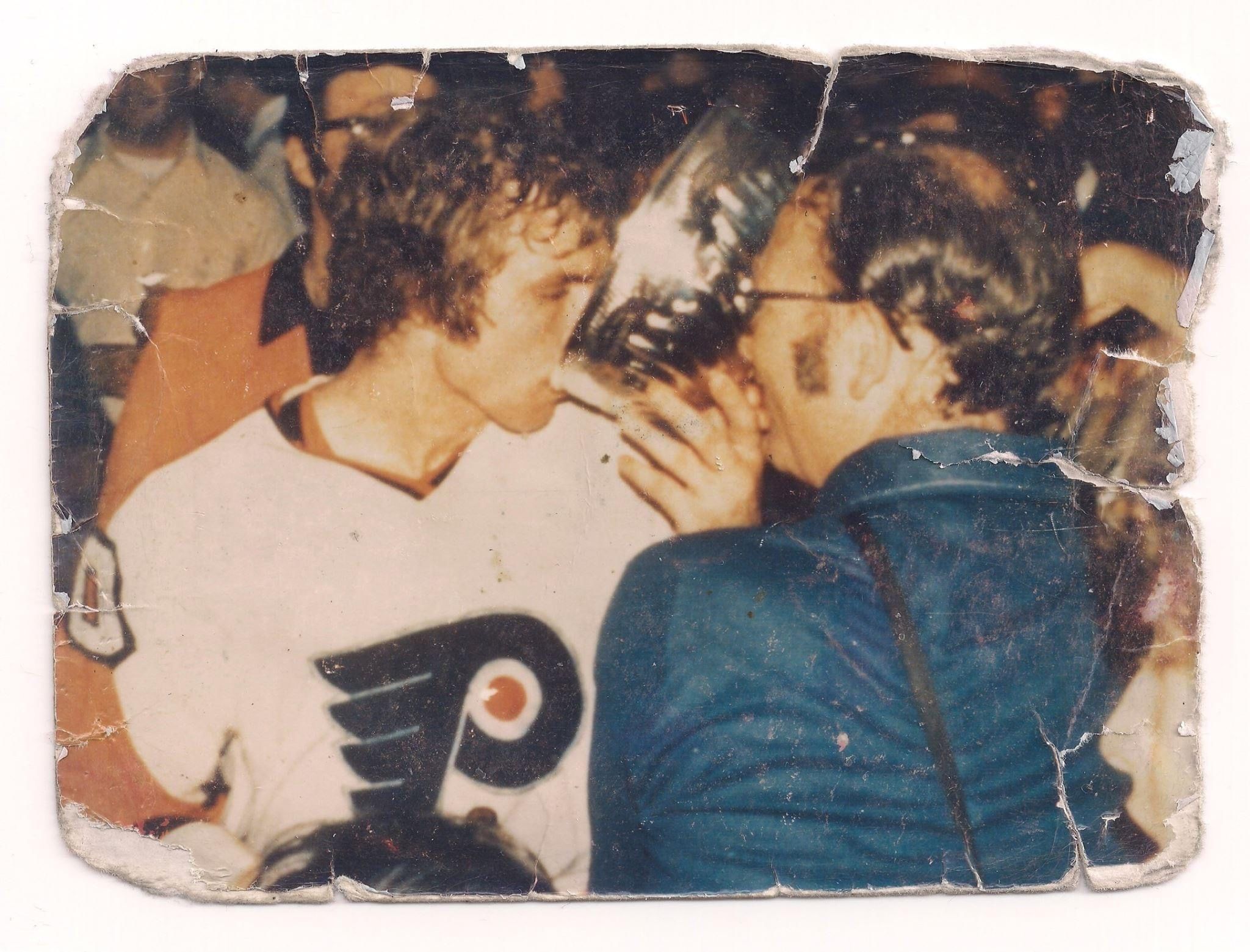 Vintage color photo of a young man with brown hair in a crowd, in a Flyers jersey, drinking out of the silver Stanley Cup