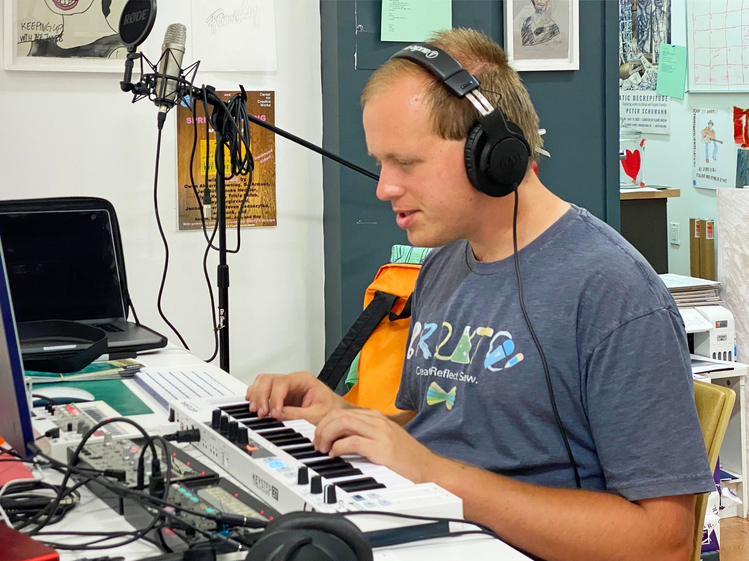 Steven, a young white man, smiling in profile as he works in a small recording studio, wearing a headset.