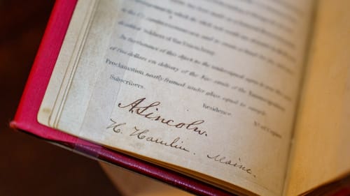 Close-up on a 19th century printed book’s page with the signature “A. Lincoln” at the bottom in ink faded to brown.