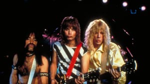 Three musicians with big hair and hold guitars and look into camera, all with straight faced with puckered lips