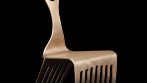 A stylish, simple bronze chair with front and back legs like an Afro pick, with the handle forming the chair’s back.