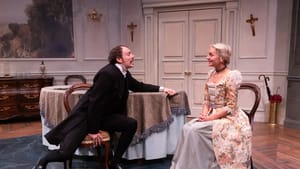 McLenigan, in historic priestly black suit, prostrates himself across a table to a smiling O’Hare, in a lacy costume dress.