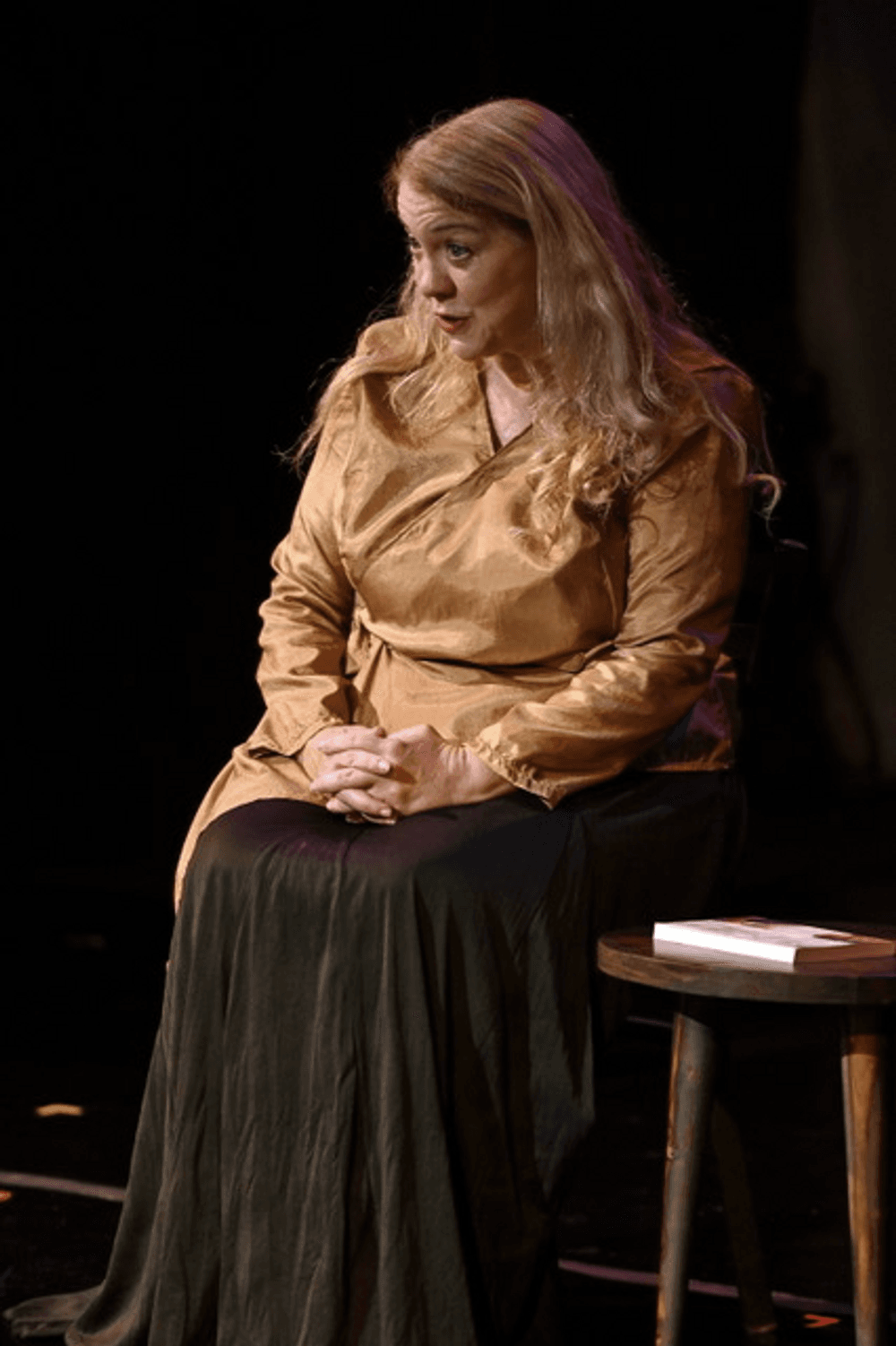 Breen, a white woman with blond hair wearing a gold top, sits and speaks with her hands folded in her lap.