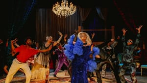 A blond drag queen in spangled blue with a giant gauze boa dances joyfully amid the lavishly costumed ensemble.