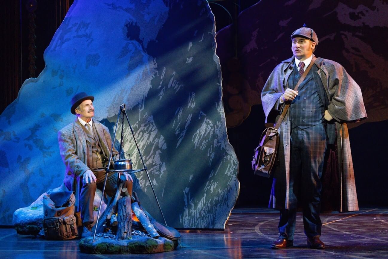 Van Horn sits at left by a faux stage campfire; Smith stands proudly in a blue plaid suit and brown plaid greatcoat.