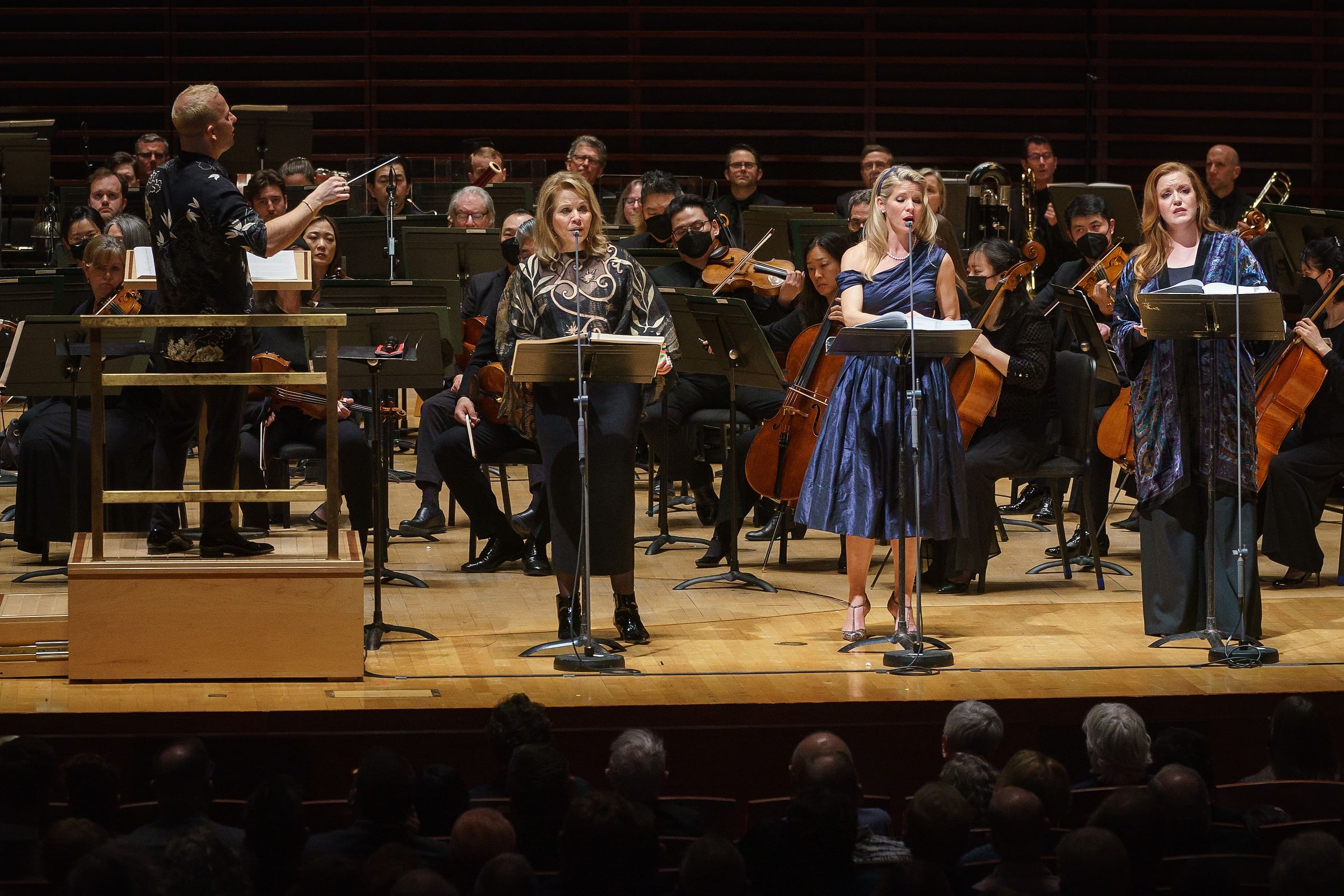 Yannick conducts the orchestra on the Verizon Hall stage. Three women singers stand at the front with mics and music stands.