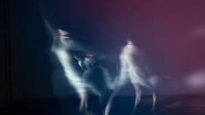 A photo exposed multiple times reveals a dancer in white in different poses mid-dance, on stage—looks like a series of ghosts