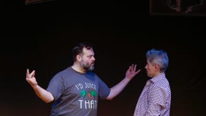 A scene from the play: Scott Greer poses as if meditating, but looks aggressively toward a concerned-looking J Hernandez.